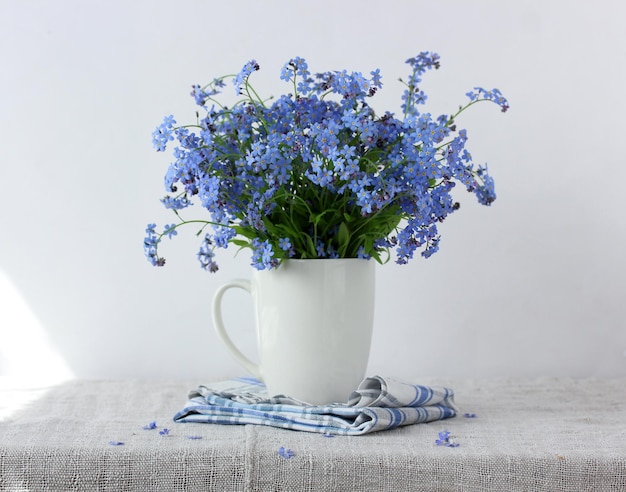 白いマグカップの夏の花の青いワスレナグサの花束