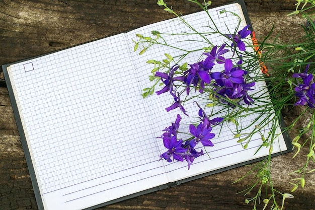 Bouquet of blue larkspur flowers and notebook for recording