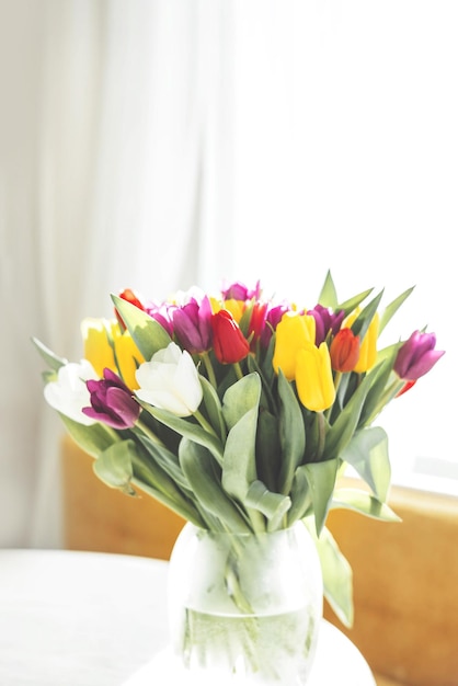 Bouquet of bright colorful tulips on white wooden table. Beautiful floral background. Spring flowers.