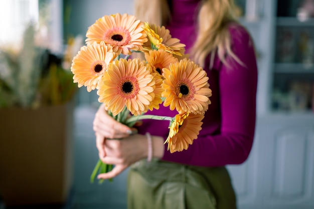 手に明るいガーベラの花束。