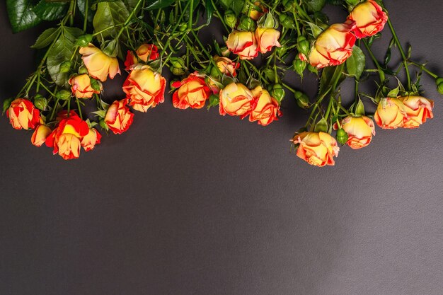 Bouquet of bright orange roses on black stone background.