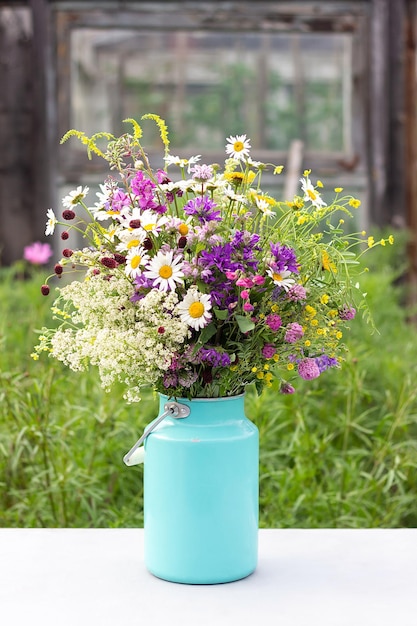 ブリキの鮮やかな野生の花の花束は、屋外のテーブルに花瓶を飾ることができます田舎のシーンはがきのテンプレートコンセプト女性の日母の日こんにちは夏またはこんにちは春