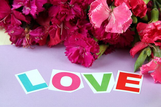 Bouquet of carnations on color wooden background