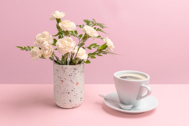 Bouquet of carnations in a vase with a cup of coffee
