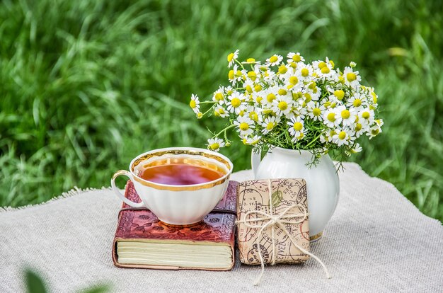 Bouquet of chamomiles, gift box and a cup of tea