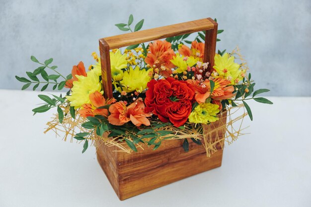 Foto bouquet di crisantemo peonia rosa e alstroemeria in confezione regalo in legno su sfondo grigio disponibile in rosso arancio e giallo