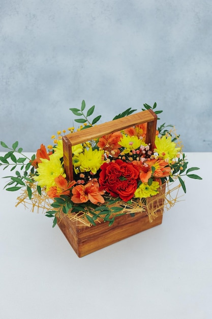 Bouquet of chrysanthemum peony rose and alstroemeria in a wooden gift box on a gray background Available in red orange and yellow