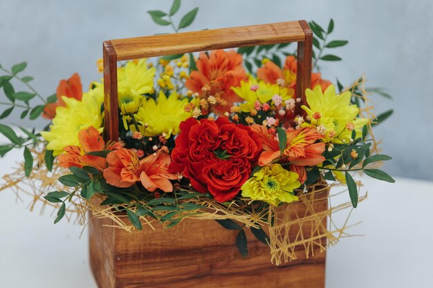 Bouquet di crisantemo peonia rosa e alstroemeria in una confezione regalo di legno su sfondo grigio disponibile in rosso arancio e giallo primo piano