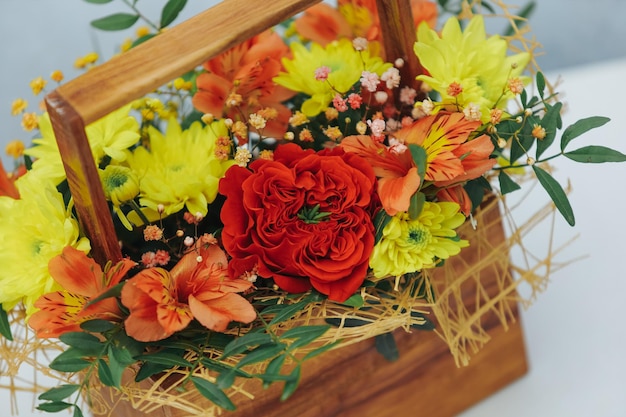 Bouquet of chrysanthemum peony rose and alstroemeria in a wooden gift box on a gray background available in red orange and yellowclose up