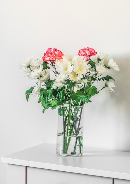 Bouquet of chrysanthemums in a glass vase on a white table