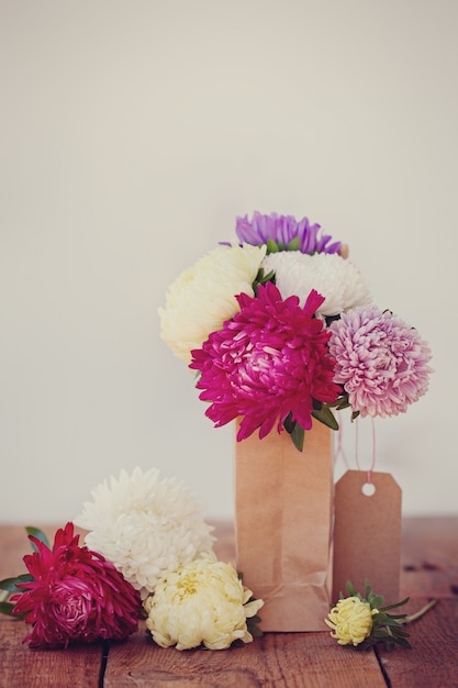 Bouquet of colorful asters in paper bag. Autumn. Toned image