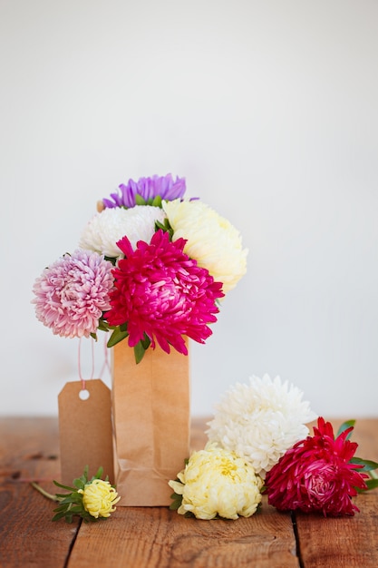 Bouquet of colorful asters in paper bag. Autumn 