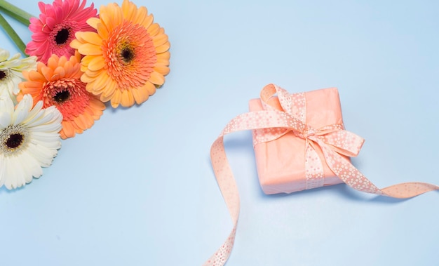 Bouquet of colorful gerberas and a small box with a gift