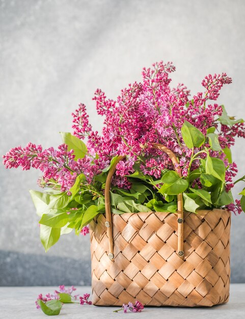 籐のバスケットに色とりどりのライラックの花の花束