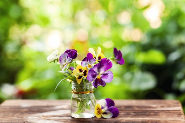 緑の自然の背景にカラフルなパンジーの花束。