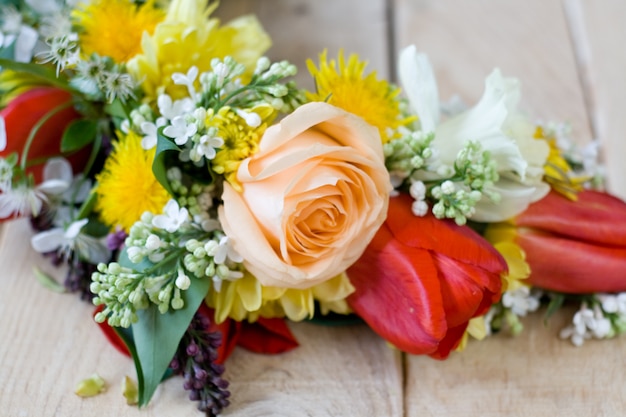 Bouquet of colorful spring flowers lying on the unpainted wooden table