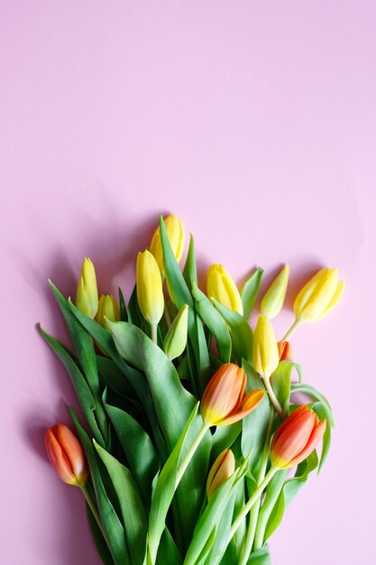 ピンクのテーブルに色とりどりのチューリップの花束。コピースペース