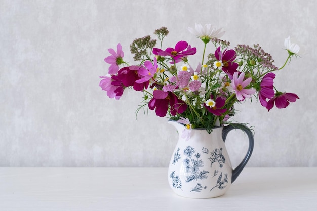 Bouquet of cosmos, milfoil and daisies on table