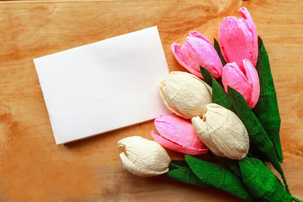 Photo bouquet of craft paper tulips and white mockup blak on wooden background mothers day or womens day greeting card