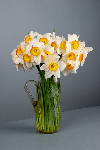 Bouquet of daffodils in a glass vase on gray surface