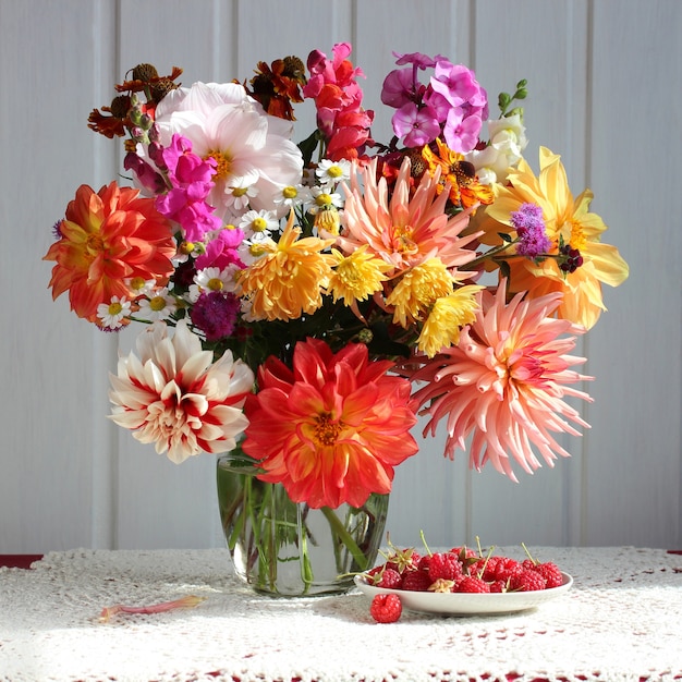 Bouquet of dahlias and raspberries on the table with lace