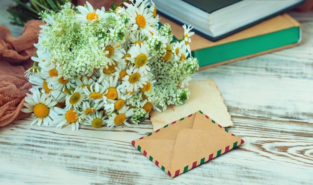 A bouquet of daisies and stack of books on a wooden background