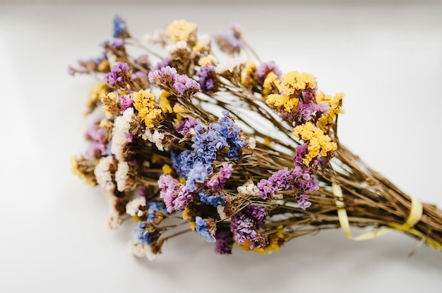 Bouquet of dried, colored flowers lying on a white