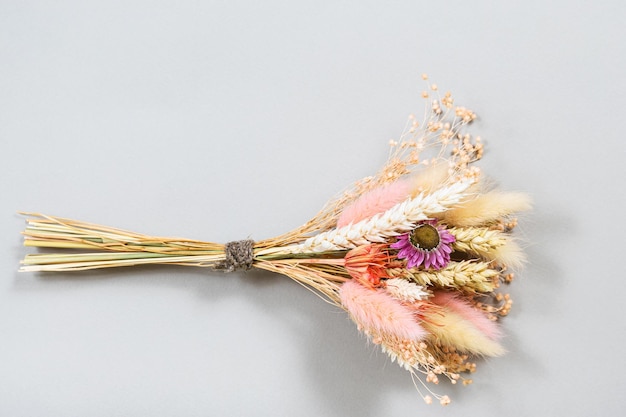 Bouquet of dried flower and spikelets lies on gray