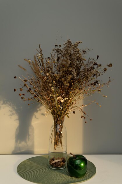 Bouquet of dried flowers on the table in a glass vase, in the\
light of the sun, contrasting image