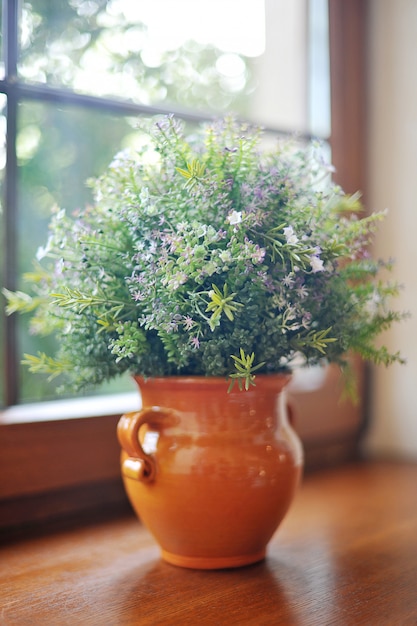 Bouquet of field flowers in a pot on the windowsill