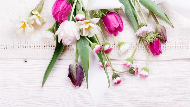 꽃다발 첫 번째 봄 꽃 분홍색 보라색 튤립 수선화와 흰색 나무 배경에 데이지 오버 헤드 상위 뷰 평면 누워 부활절 생일 어머니의 발렌타인 여성의 결혼식 개념