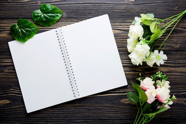 Bouquet of flower and empty diary notebook on rustic wooden table with copy space.