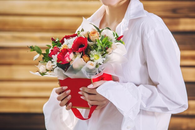 木製の背景に若い女の子モデルの手で花の花束のクローズアップ