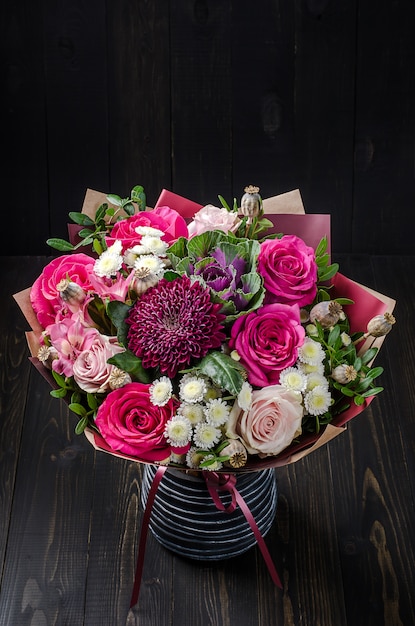 Un mazzo di fiori su un fondo di legno scuro. bouquet con rose.