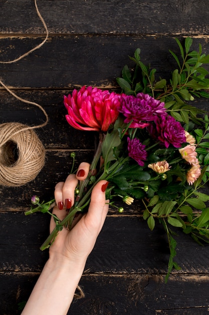 Bouquet of flowers in female hand on a black wooden table