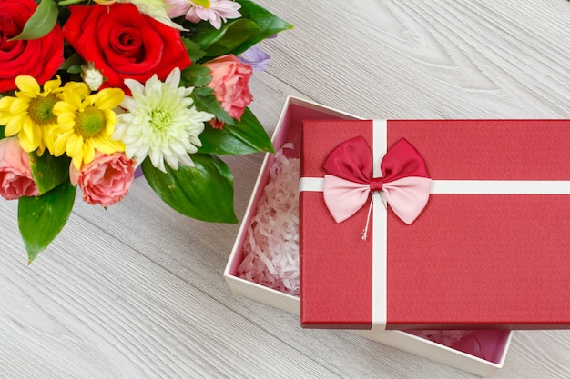 Bouquet of flowers and a gift box on the gray wooden boards