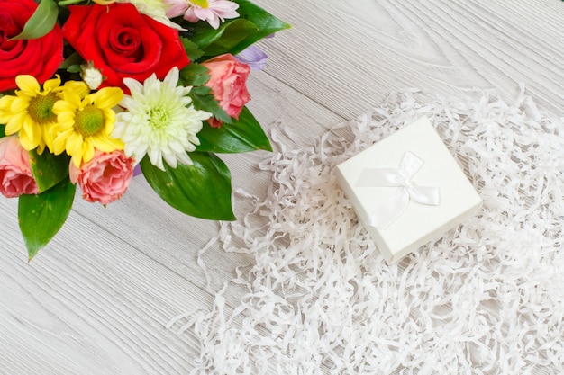 Bouquet of flowers and a gift box on a white napkin. top view