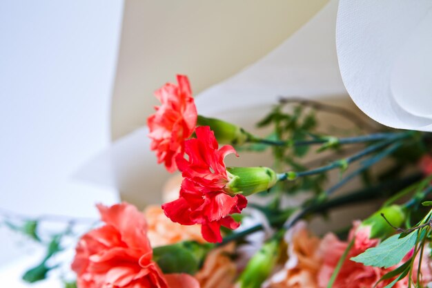 A bouquet of flowers is in a box with a paper bag in the background.