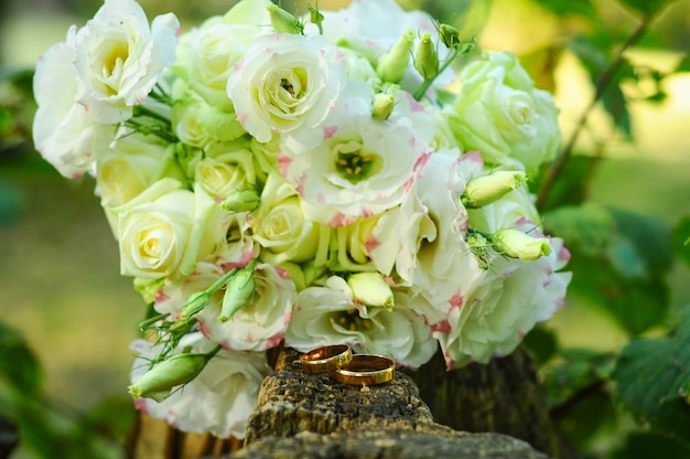 A bouquet of flowers is on a log with a ring on it