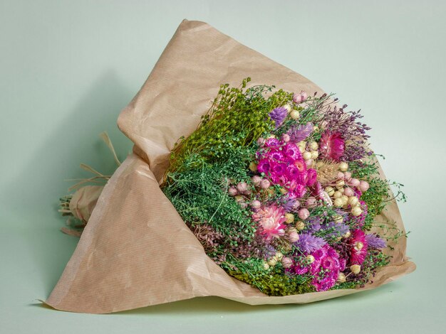 A bouquet of flowers is wrapped in brown paper.