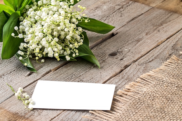 Bouquet of flowers lily of the valley and empty paper sheet