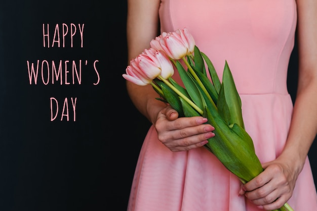 Photo bouquet of flowers of pink tulips in the hands of a girl