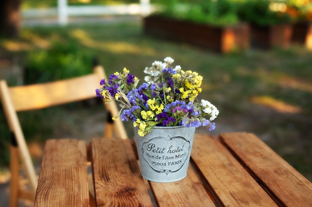 庭の木製テーブルにヴィンテージの花瓶の花の花束