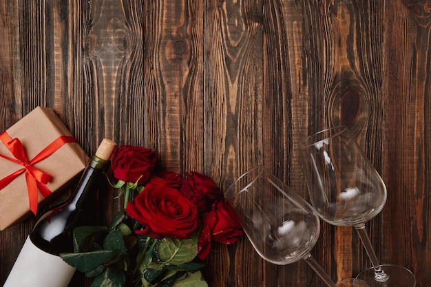 bouquet of flowers wine and gifts on a wooden background