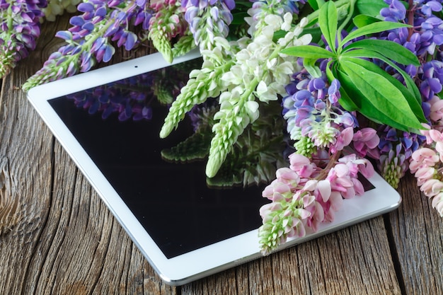 Bouquet of flowers on a wooden table with a tablet computer