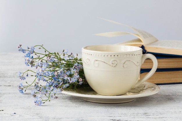 Bouquet of forget me not flowers and old books on wooden table