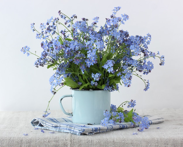 Bouquet of forget-me-nots in a blue mug. delicate summer composition.