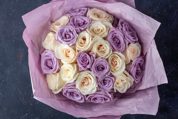 Bouquet of fresh amazing white and purple roses in craft paper