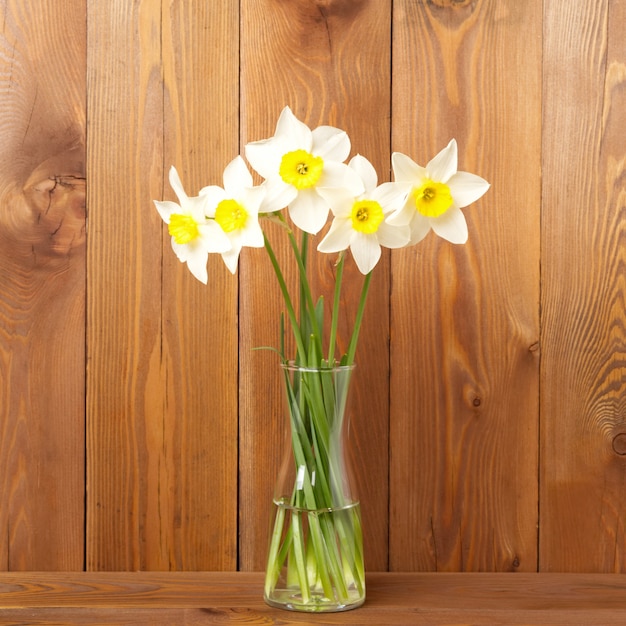 Bouquet of fresh flowers, daffodils in vase in the middle of wooden table