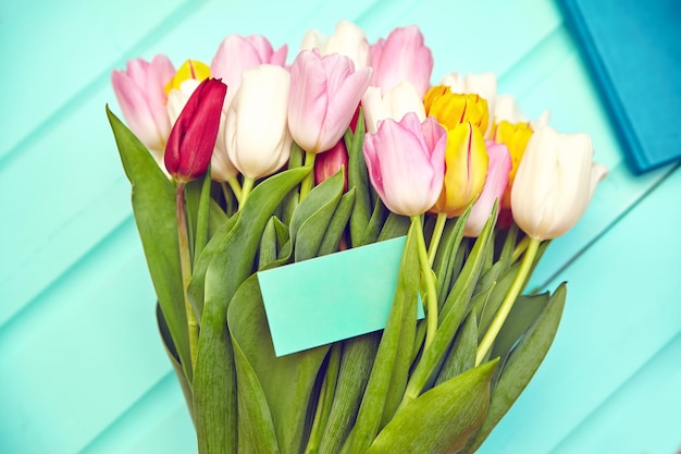 Bouquet of fresh multicolor tulip flowers on old blue wooden table